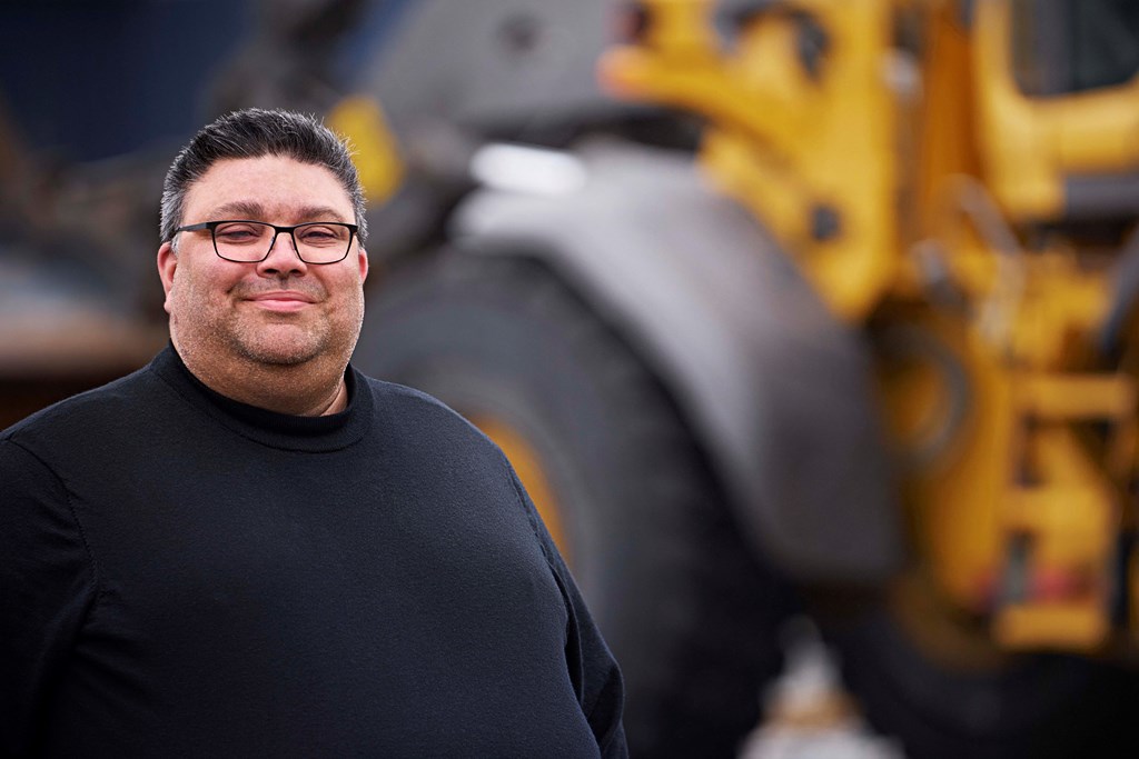 Karl Hoffman står foran en gravemaskin.