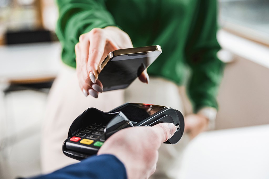 Person making a contactless payment with a smartphone.