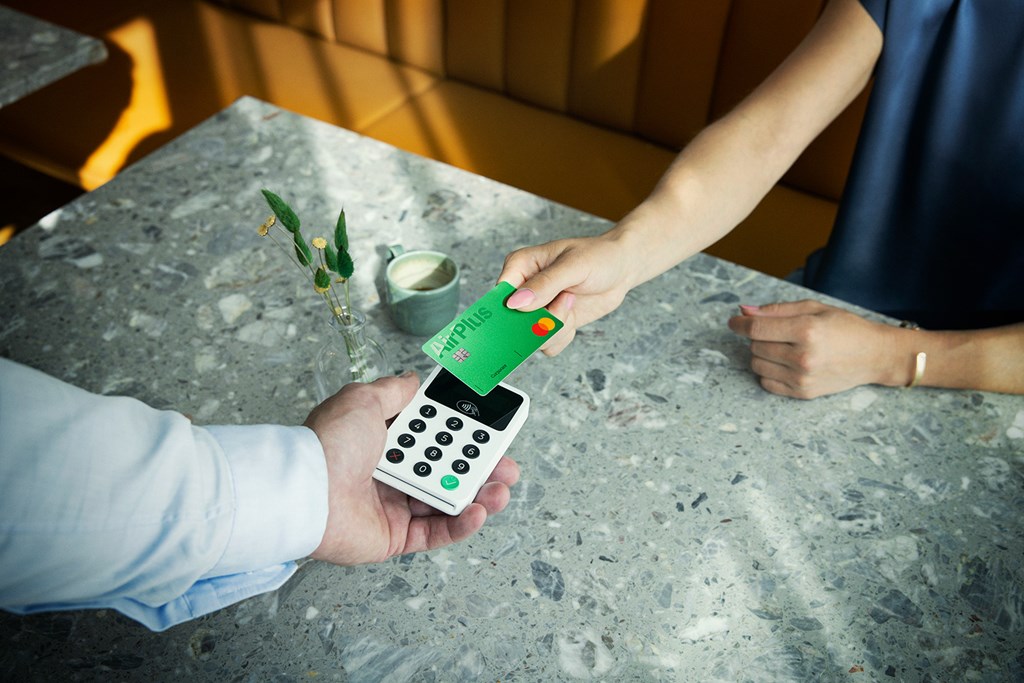 Person making a contactless payment with a smartphone displaying an AirPlus Corporate Card.